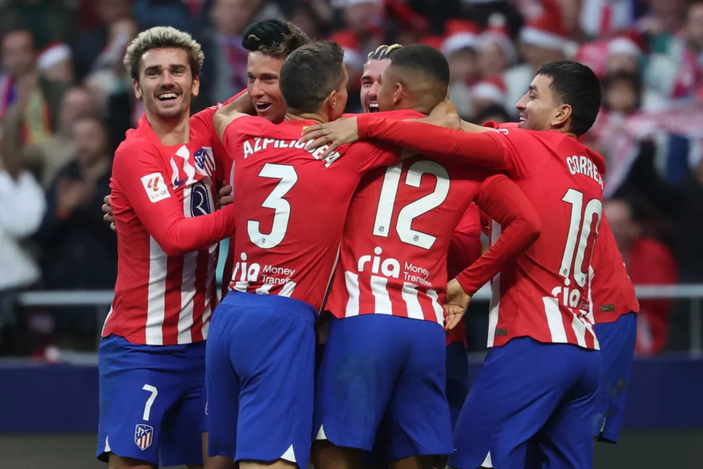 Atletico Madrid's Spanish midfielder #14 Marcos Llorente celebrates scoring his team's first goal with teammates, including Atletico Madrid's French forward #07 Antoine Griezmann (L), during the Spanish league football match against Sevilla FC at the Metropolitano stadium on December 23, 2023