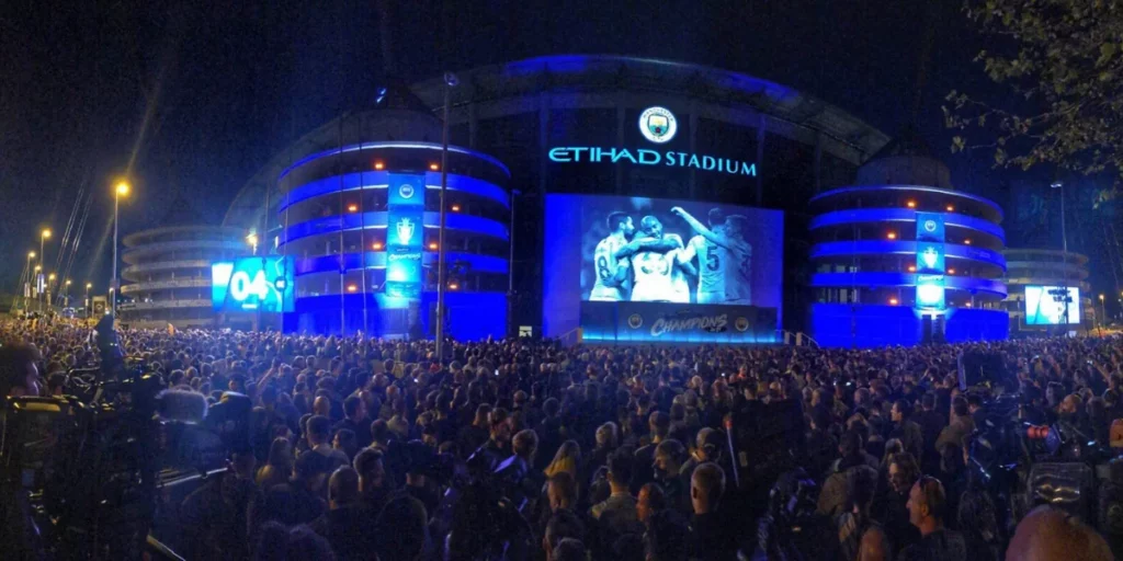 Etihad Stadium at night lit in Sky Blue